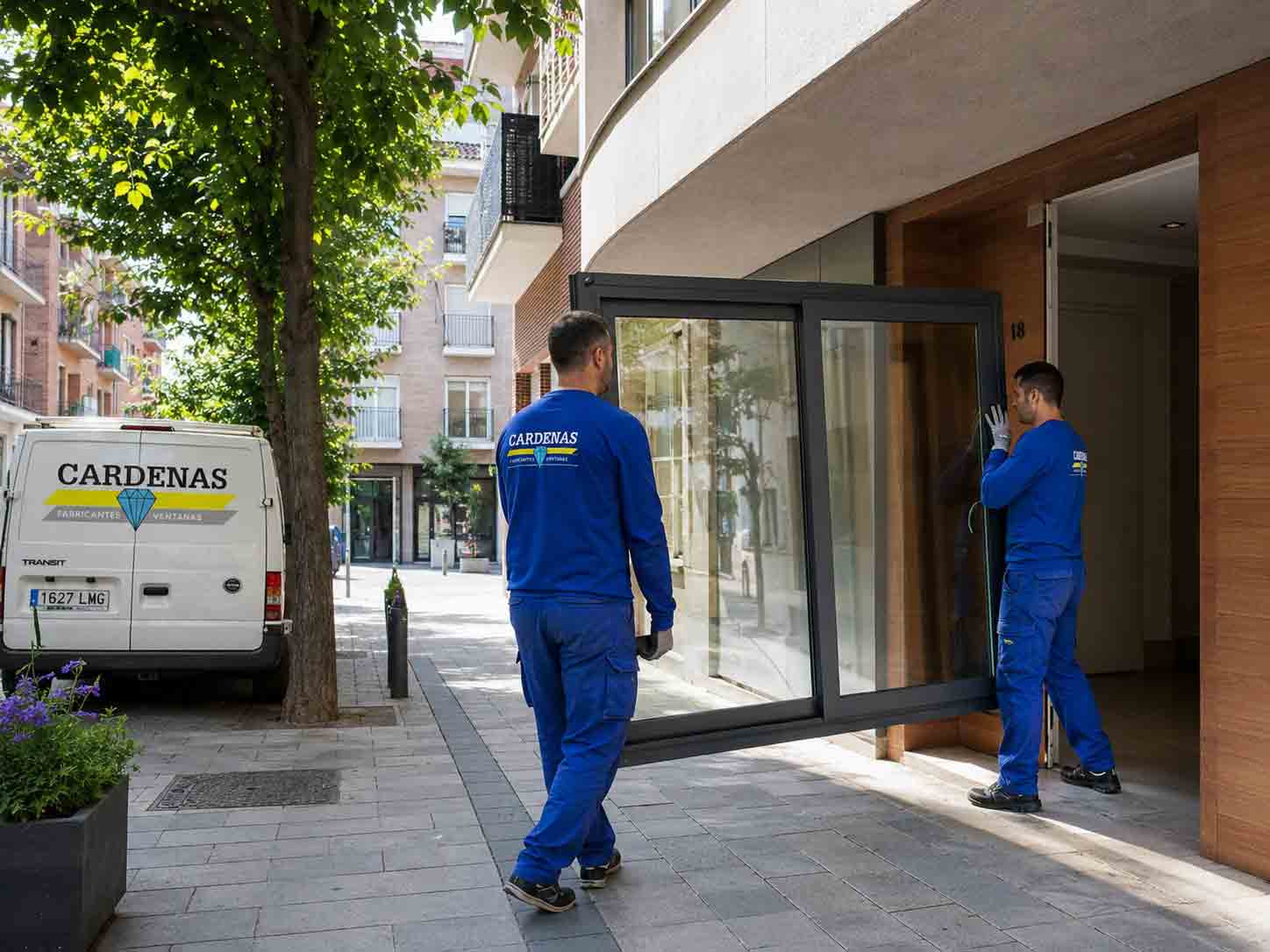 Operarios llevando una ventana de aluminio por la calle de Esplugues de Llobregat para instalarla en una vivienda